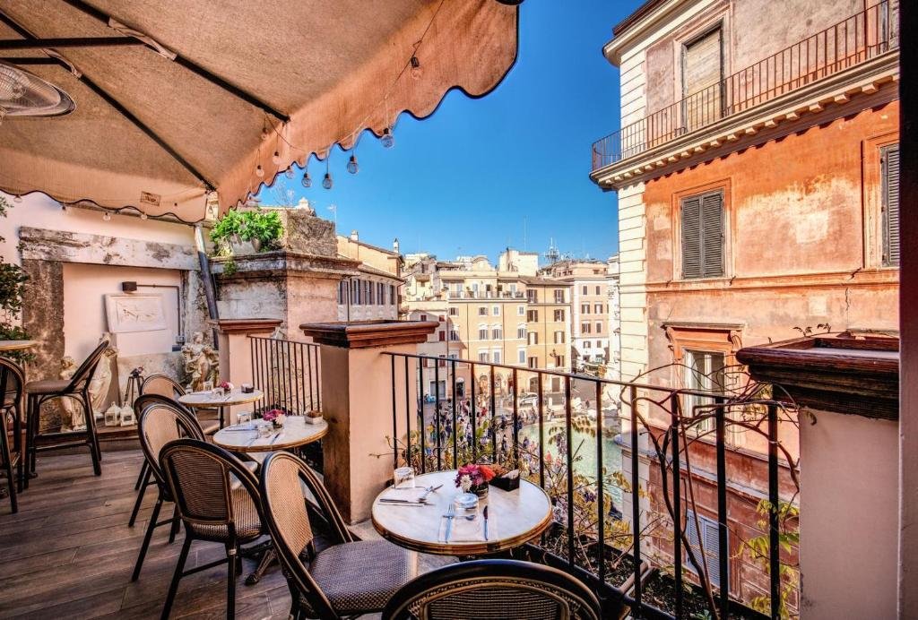 terraço do Relais Fontana Di Trevi Hotel com mesinhas redondas e cadeiras de ferro, contando ainda com esculturas pequenas e vista direta para a Fontana di Trevi