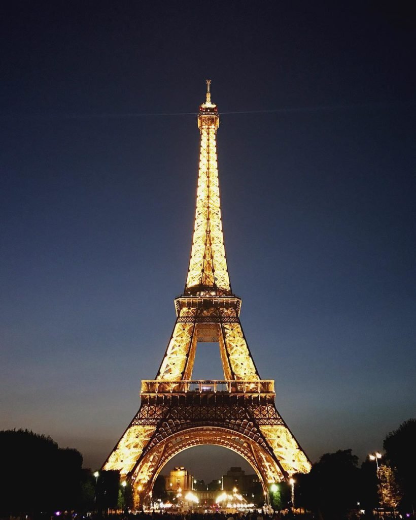 Foto da frente da Torre Eiffel iluminada à noite, uma das opções de o que fazer em Paris.