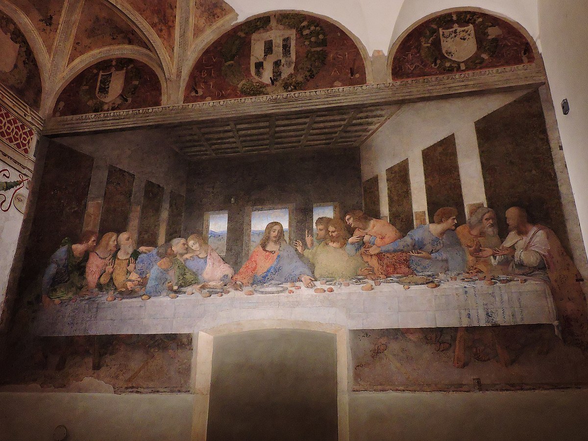 Pintura a Última Ceia de Leonardo da Vinci na parede da igreja Santa Maria delle Grazie. Ela retrata Jesus e os discípulos sentados em uma longa mesa, situada em uma sala com tetos abobadados. Essa é uma das atrações imperdíveis entre as opções de o que fazer em Milão.