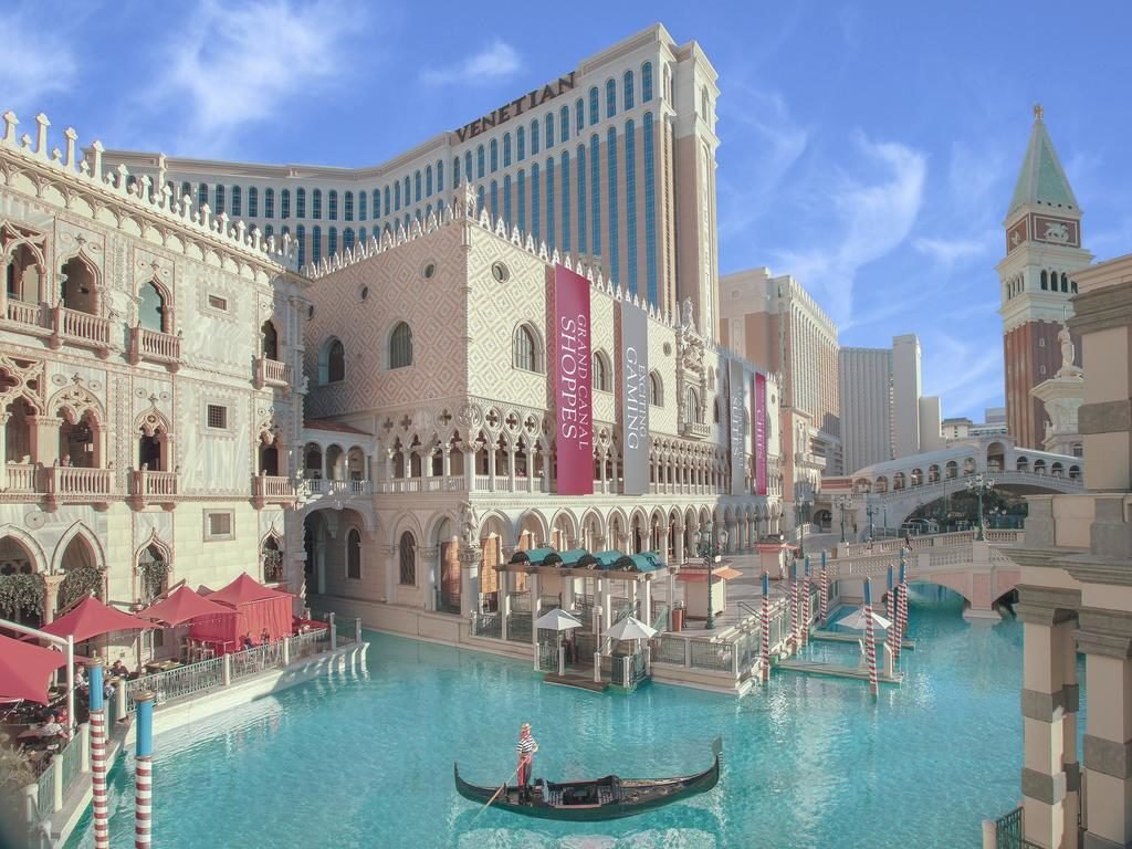 Canal no The Venetian que remete ao canal de Viena. O hotel fica em volta da água, que é bem azul e passa embaixo também de uma ponte. Uma gôndola com um guia remando passa pela água.