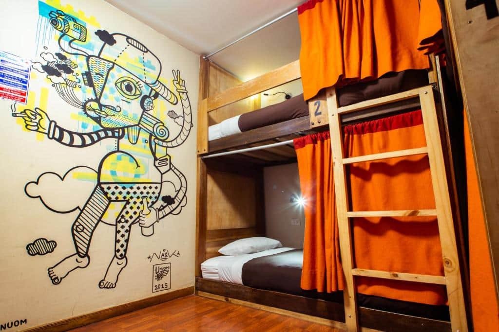 dormitório do Viajero Kokopelli Cusco Hostel com duas camas em uma beliche, no lado direito da imagem. No lado esquerdo há uma parede grafitada com um garoto.