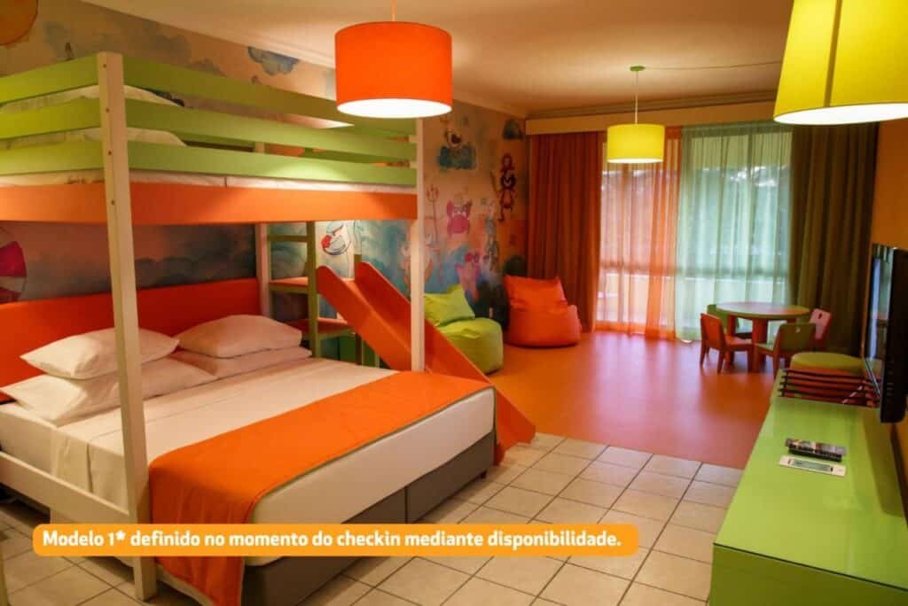 Quarto da Vila Galé Eco Resort do Cabo - All Inclusive colorido com um beliche acima de uma cama de casal, decoração laranja, pufes e uma pequena mesa com cadeiras perto da janela.