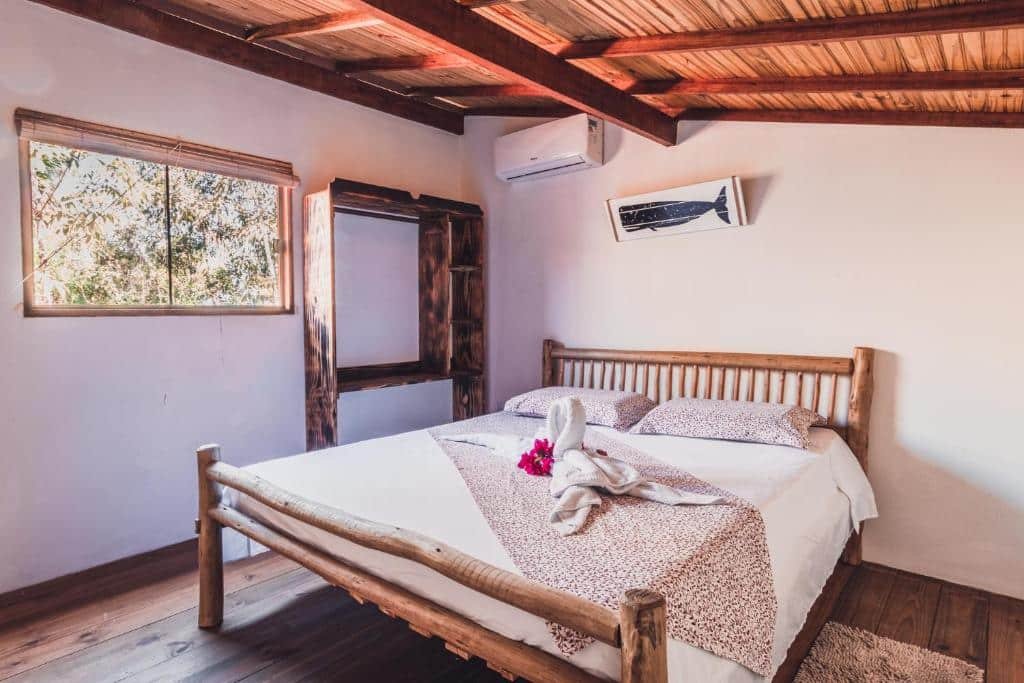 Foto do quarto na Vila Piê. A cama de casal está no meio. Há um ar-condicionado no topo. Na direita há um armário e janela. Representa o post sobre airbnb em Itacaré.