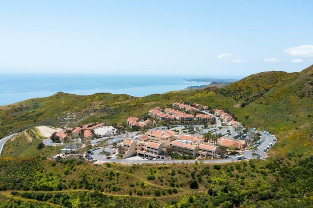 Vista aérea do Villa Graziadio Executive Center. Montanhas ao redor, uma pequena cidade e o hotel, no fundo a vista do mar. Foto para ilustrar post sobre hotéis em Malibu na Califórnia.