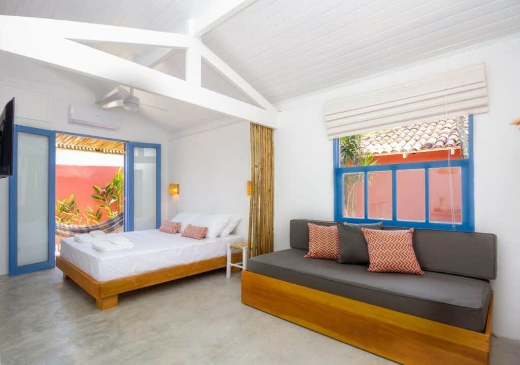 Quarto espaçoso no Villa Tennis com uma varanda com rede, uma cama de casal, uma janela e um sofá, tudo em estilo rústico 