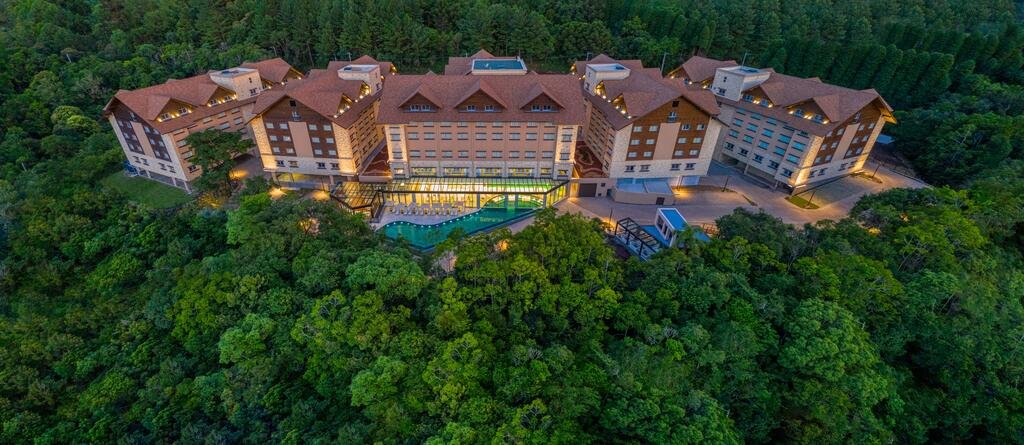 vista aérea do Wyndham Termas Resort & Spa com seis construções grandiosas no centro, rodeadas por muitas árvores verdes e frondosas.