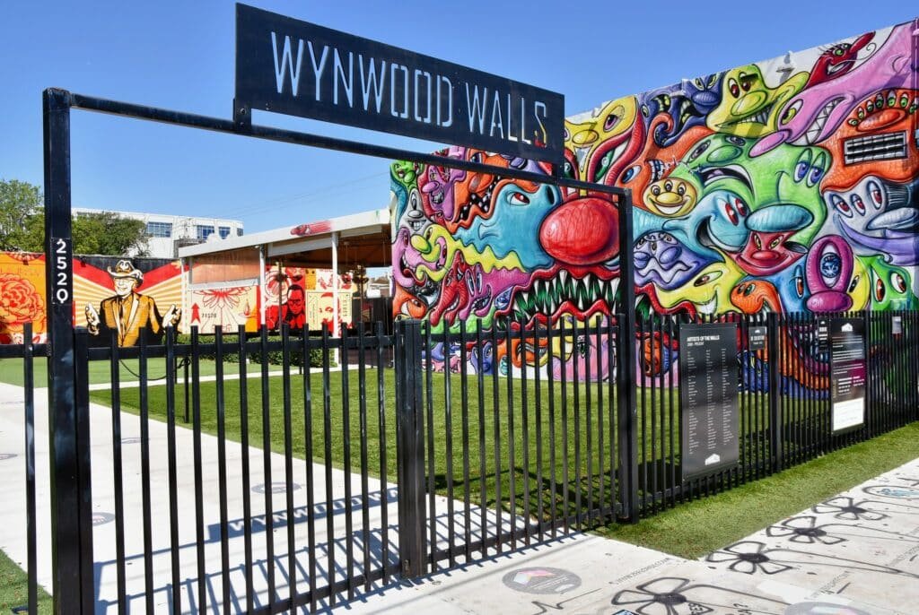 Porta de entrada de Wynwood Walls. Depois dele estão alguns murais com artes, todos bem coloridos e diferentes. É uma ótima opção de o que fazer em Miami.